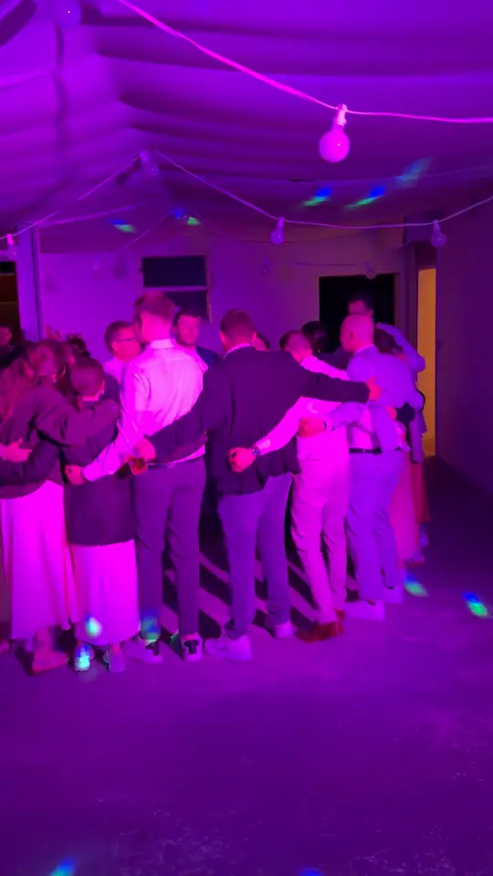 Gäste stehen Arm in Arm im Kreis und singen mit